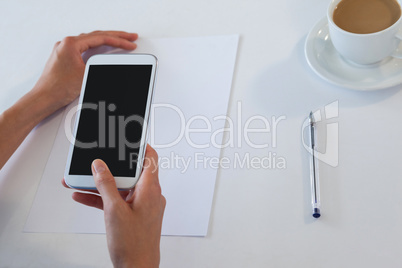 Businesswoman using smart phone at table