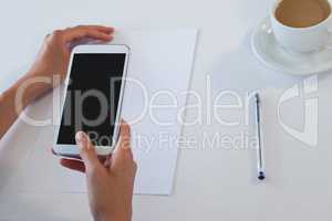 Businesswoman using smart phone at table