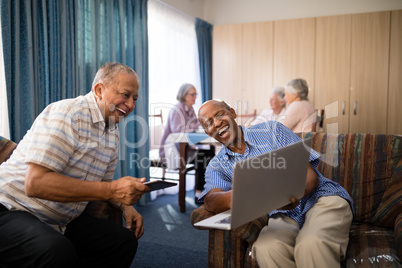 Happy senior friends looking at laptop