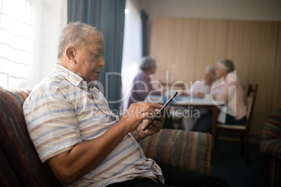 Senior man using mobile phone on sofa