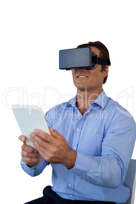 Businessman with tablet sitting on chair while using vr glasses