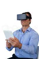Businessman with tablet sitting on chair while using vr glasses
