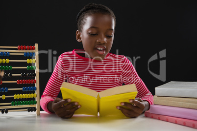 Schoolgirl reading a book against black background