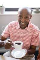 High angle portrait of smiling senior man having coffee