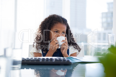 Businesswoman with curly hair looking away while drinking coffee