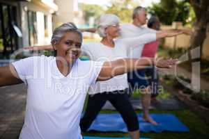 Smiling senior woman doing stretching exercise with friends