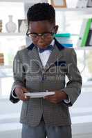 Serious businessman using mobile phone against shelf