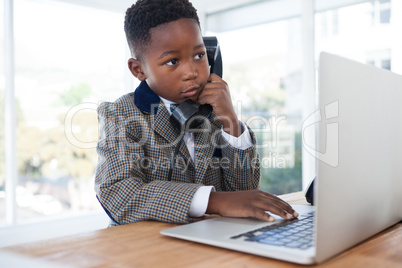 Businessman talking on telephone while using laptop