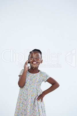 Smiling businesswoman with hand on hip while talking on mobile phone