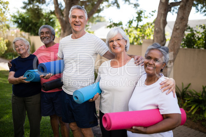 Portrait of happy multi-ethnic friends carrying exercise mats