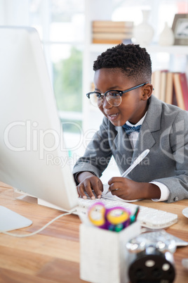 Smiling businessman writing report while looking at computer