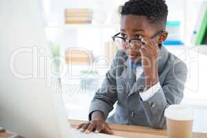 Boy imitating as businessman using computer in office