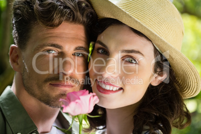 Smiling couple holding flower in garden