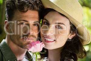 Smiling couple holding flower in garden