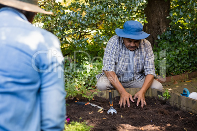 Couple planting young plant into the soil