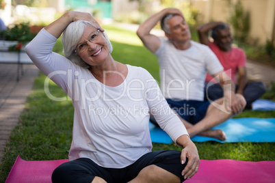 Smiling woman stretching head while exercising with friends