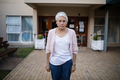 Portrait of serious senior woman standing on entrance