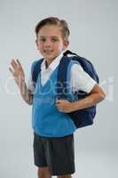 Portrait of cute school boy waving hand