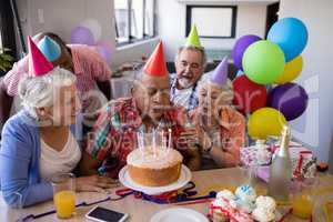 Senior man blowing candles on birthday cake