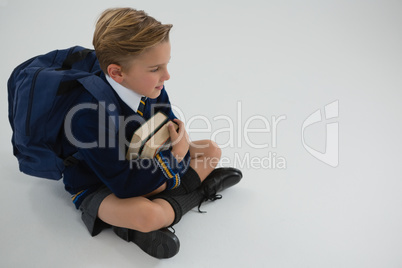 Schoolboy sitting with books on white background