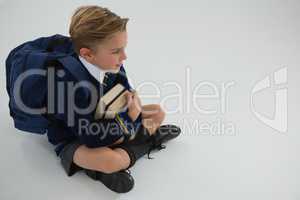 Schoolboy sitting with books on white background