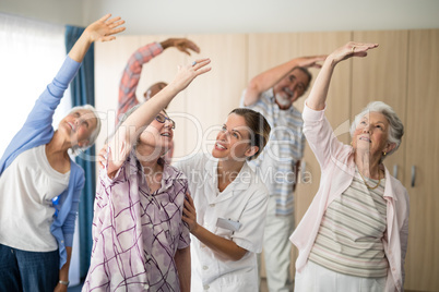 Smiling female doctor assisting senior woman exercising