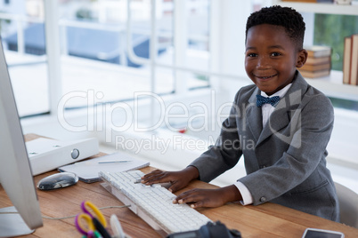 Portrait of smiling businessman using computer at desk