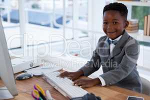 Portrait of smiling businessman using computer at desk