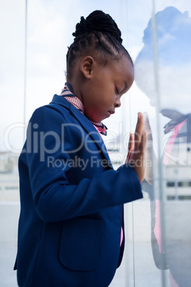 Thoughtful businesswoman with closed eyes standing by glass window