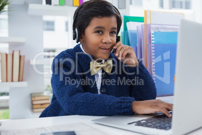 Businessman using head set while working on laptop