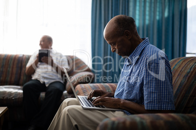 Senior man using laptop while sitting on sofa