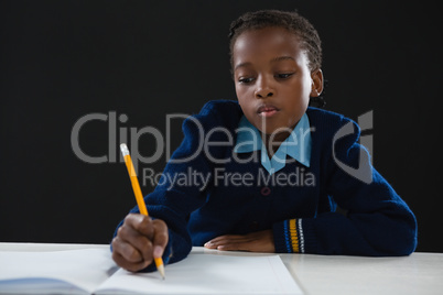 Schoolgirl doing her homework against black background