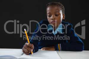 Schoolgirl doing her homework against black background