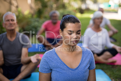Trainer and senior people meditating with closed eyes