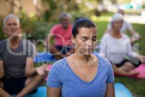 Trainer and senior people meditating with closed eyes