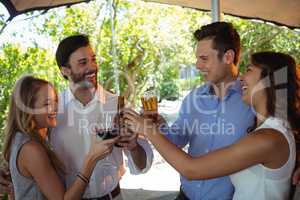 Friends interacting while toasting glass and bottle of alcohol at counter