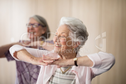Smiling senior women with hands clasped looking away