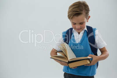 Schoolboy reading book against white background