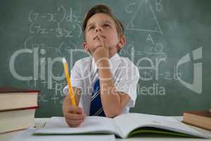 Schoolboy doing his homework in classroom