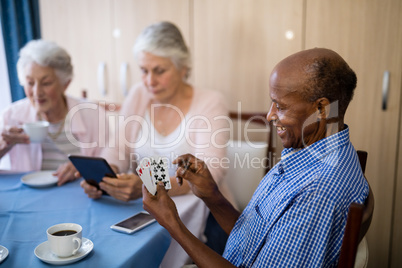 Senior man playing cards with friends while having coffee