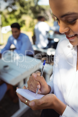 Smiling waitress writing order on notepad