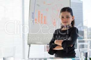 Portrait of smiling businesswoman with arms crossed standing by whiteboard