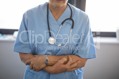 Mid section of senior doctor wearing scrubs and stethoscope