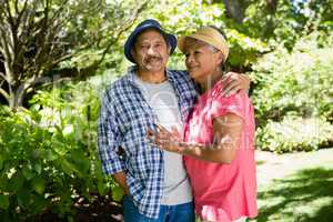 Portrait of senior couple standing with arm around in garden