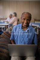 Portrait of happy senior man using laptop