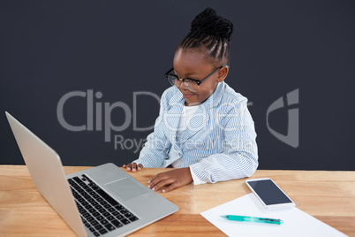 Smiling businesswoman wearing eyeglasses looking laptop