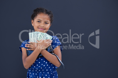 Portrait of smiling girl embracing currency