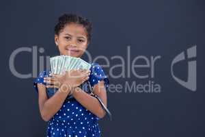 Portrait of smiling girl embracing currency