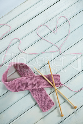 High angle view of pink Breast Cancer Awareness ribbon by crochet needles with heart shape