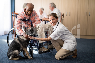 Portrait of female doctor kneeling by disabled senior man stroking puppy